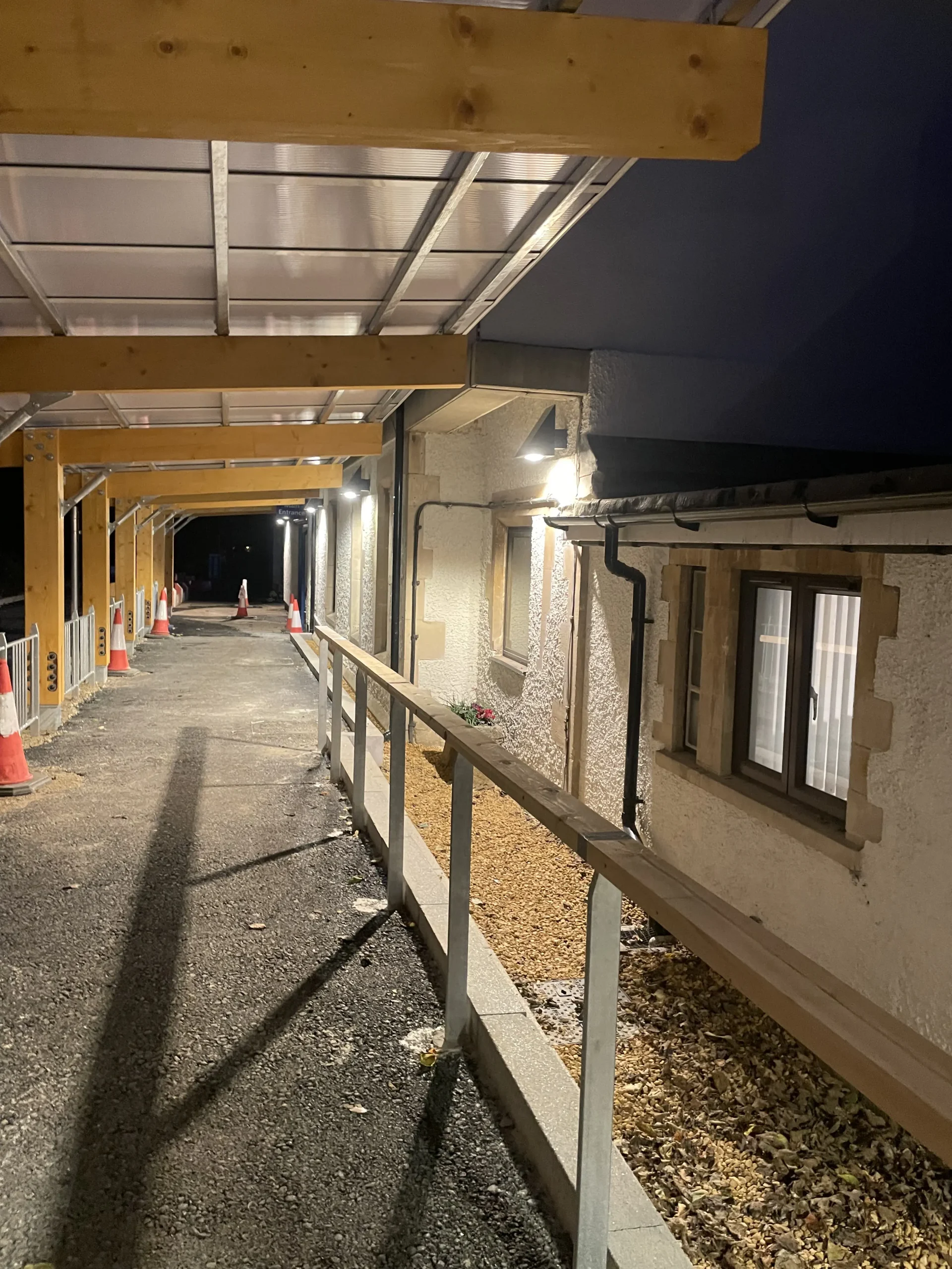 Night view of the same walkway as in image 5, shown from another angle highlighting the lighting and the wooden structure of the walkway.