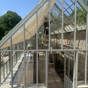Evening view of the Hartley Botanic greenhouse and walled garden lit by warm white wall lights