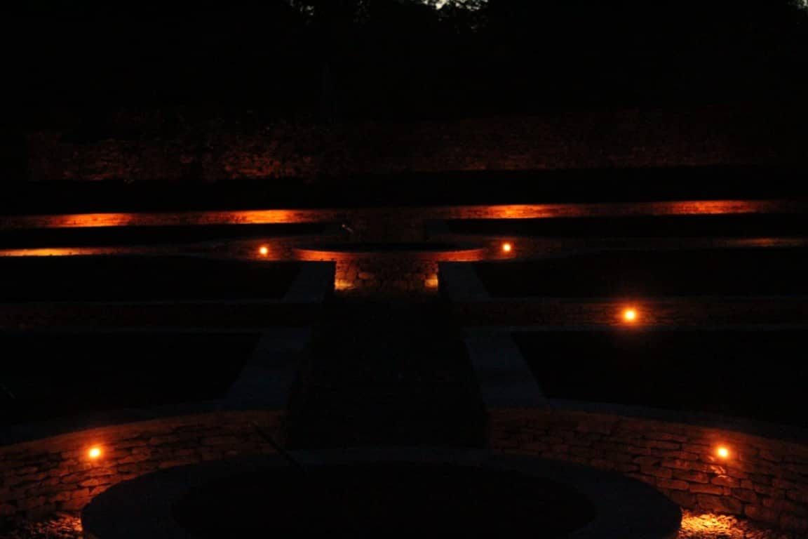 Walled garden walkway softly lit by recessed wall lights at dusk