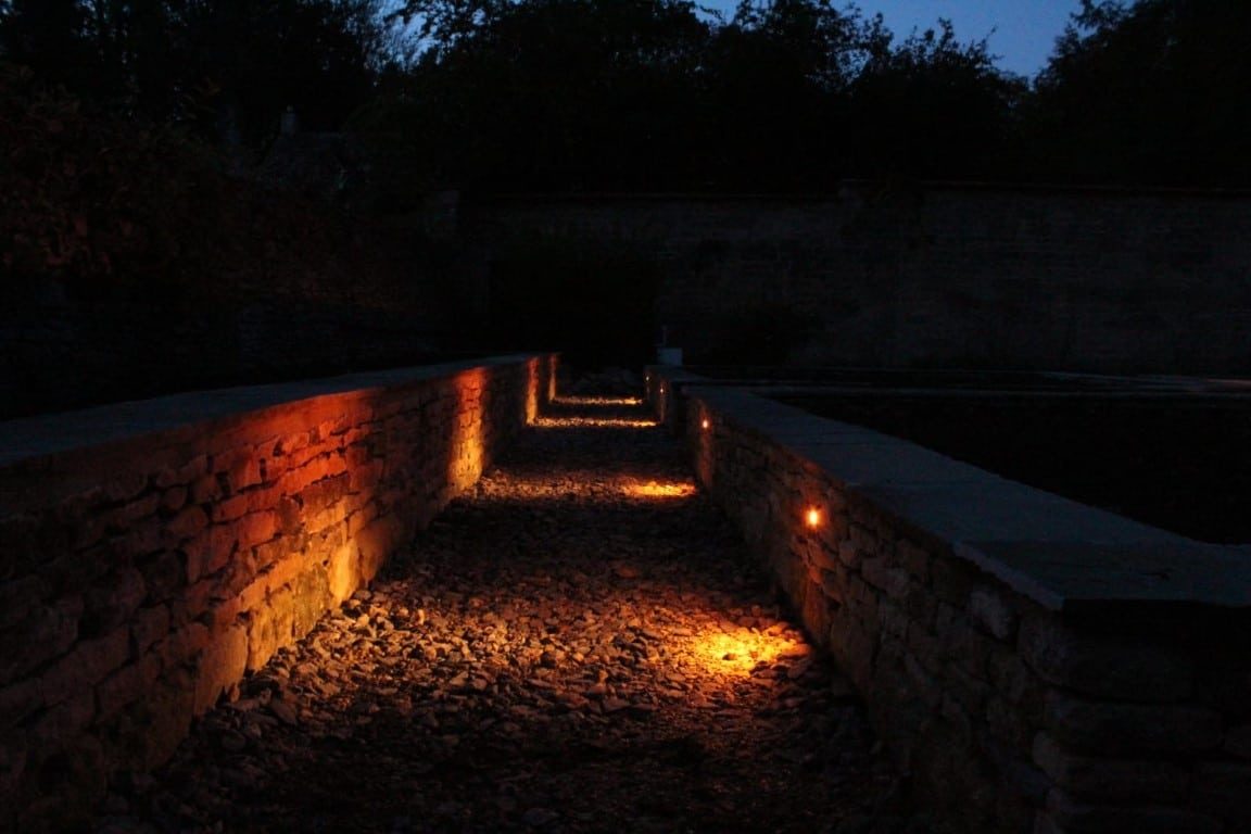Evening view of the Hartley Botanic greenhouse and walled garden lit by warm white wall lights